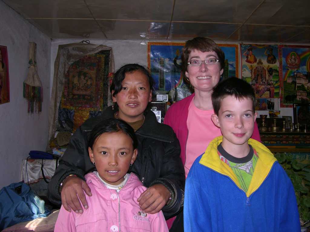 Tibet Guge 01 To 04 Sangsha Girls Charlotte and Peter pose with the daughters of the owner of the restaurant and room at Sangsha. The elder Nyima Dolma is behind and the very cute 11-year-old Tashi Sangmo is in front. Tashi spends nine months years away at school, a 10-hour drive towards Ali.